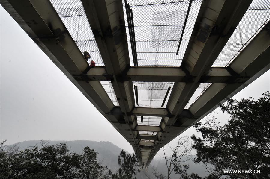 Photo taken on Jan. 18, 2016 shows the glass bridge across the Zhangjiajie Grand Canyon under construction in Zhangjiajie, central China's Hunan Province, Jan. 18, 2016. The bridge is 430 meters long, six meters wide and 300 meters above the valley. It is capable of holding 800 people at once and is expected to be opened to tourists in the first half of this year. [Xinhua]