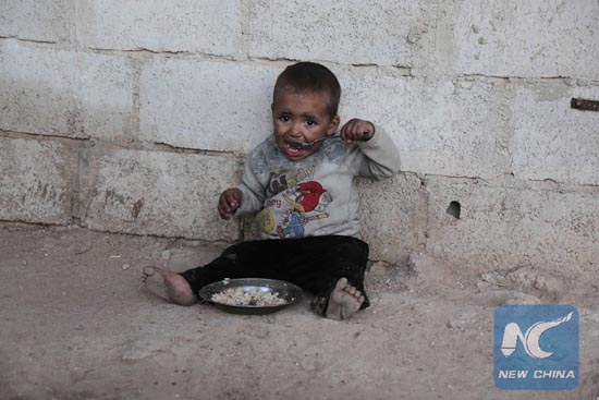 A child from the Abu Sleiman family has a lunch at his house in the Syrian town of Beit Nayem, in the rebel-held Eastern Ghouta region on the outskirts of the capital Damascus,on January 13, 2016. [Photo/Xinhua]
