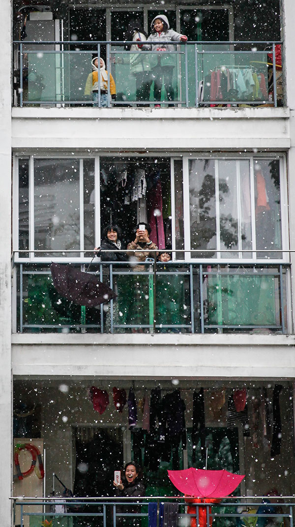 Residents enjoy the snow from their balconies in Panyu, Guangdong province, on Sunday. [Photo/China Daily]