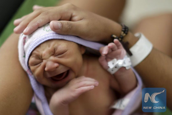 Sueli Maria (obscured) holds her daughter Milena, who has microcephaly, (born seven days ago), at a hospital in Recife, Brazil, January 28, 2016. Milena was born with microcephaly, a neurological disorder that damaged her brain and also affected her vision, a condition associated with an outbreak of Zika virus in Brazil. [Photo/Xinhua]