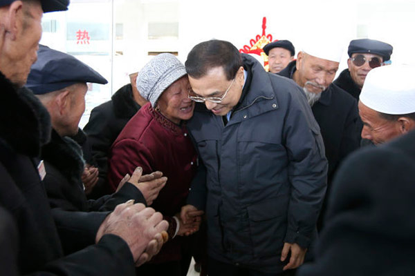 A senior citizen holds Premier Li Keqiang's hand as she talks with him at the nursing home, Feb 1, 2015. [Photo/English.gov.cn] 
