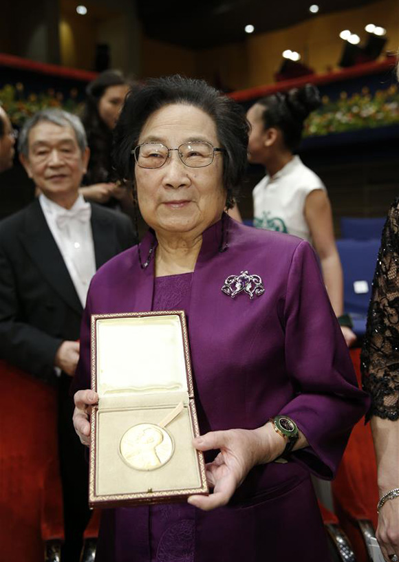 2015's Nobel laureate in Physiology or Medicine Tu Youyou (L) shows her medal following the Nobel Prize award ceremony at the Concert Hall in Stockholm, capital of Sweden, Dec. 10, 2015. [Photo/Xinhua] 