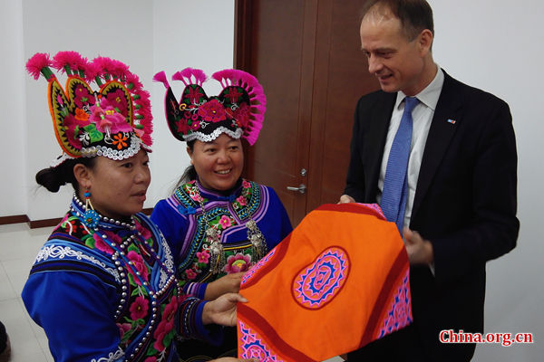 Patrick Haverman, deputy director of UNDP in China, buys an embroidery art work from the women of the Yi ethnic group on Tuesday in Beijing. [Photo by Chen Boyuan / China.org.cn]
