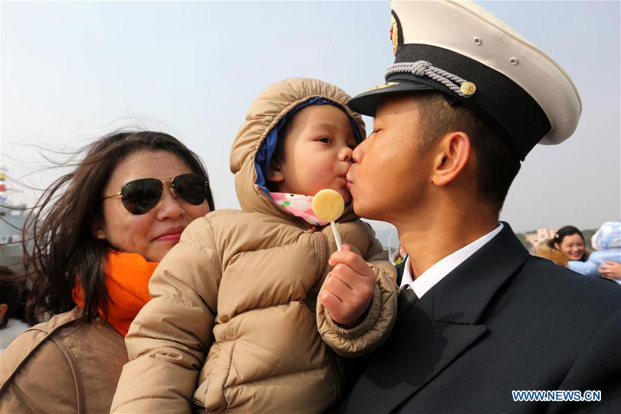 A naval officer kisses his child as he gets off board in a military port in Zhoushan, east China's Zhejiang Province, Feb. 5, 2016.[Photo/Xinhua]