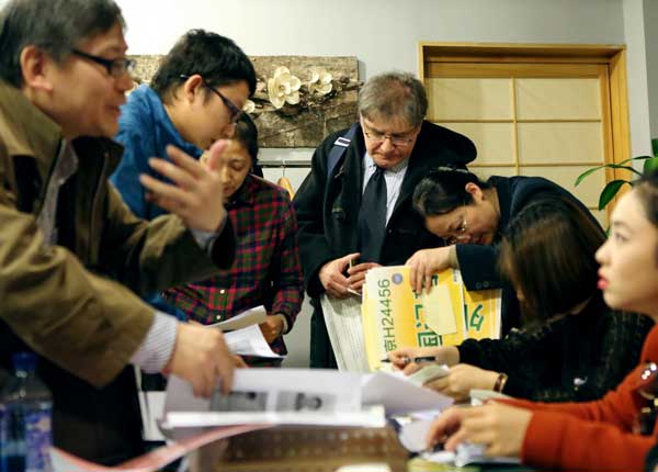 Andrey Kirillov (center), of Russian news agency ITAR-Tass, and other journalists receive their press cards for the upcoming two sessions in Beijing on Tuesday.[Photo/China Daily]