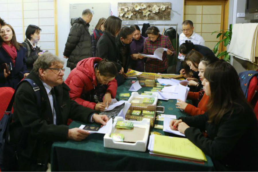 Andrew Kirillov, left, Beijing bureau chief of Russia's Itar-Tass News Agency, receives press credentials for the two sessions at the Media Center Hotel in Beijing, March 1, 2016. The annual meetings of the National Committee of the Chinese Political Consultative Conference (CPPCC) and the National People's Congress (CPC) will start on March 3 and 5 respectively. [Photo by Kuang Linhua/ chinadaily.com. cn]