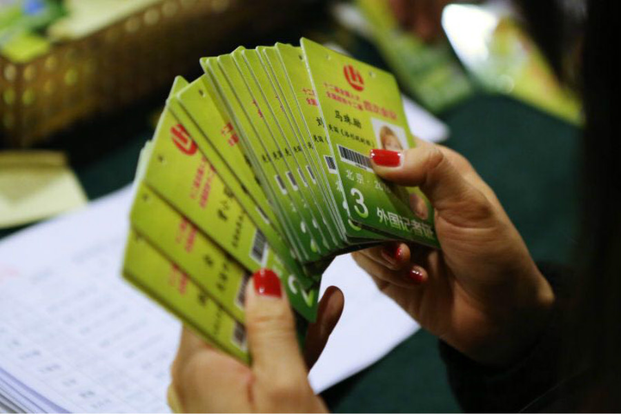 A member of staff holds press cards for foreign journalists at the Media Center Hotel in Beijing, March 1, 2016. [Photo by Kuang Linhua/chinadaily.com.cn]