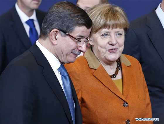 Turkish Prime Minister Ahmet Davutoglu (L) and German Chancellor Angela Merkel speak as they and EU leaders gather for a group photo during an extraordinary summit of European Union leaders with Turkey at the European Council headquarters in Brussels, Belgium, March 7, 2016. [Photo/Xinhua]