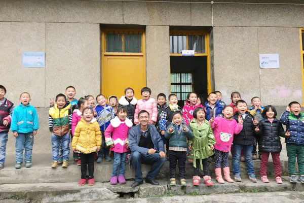Ge Yike, one of the initiators for the charity project'One School One Dream', with pupils of Shima primary school in Badong county, Central China's Hubei province, Oct 2015. [Photo provided to chinadaily.com.cn]