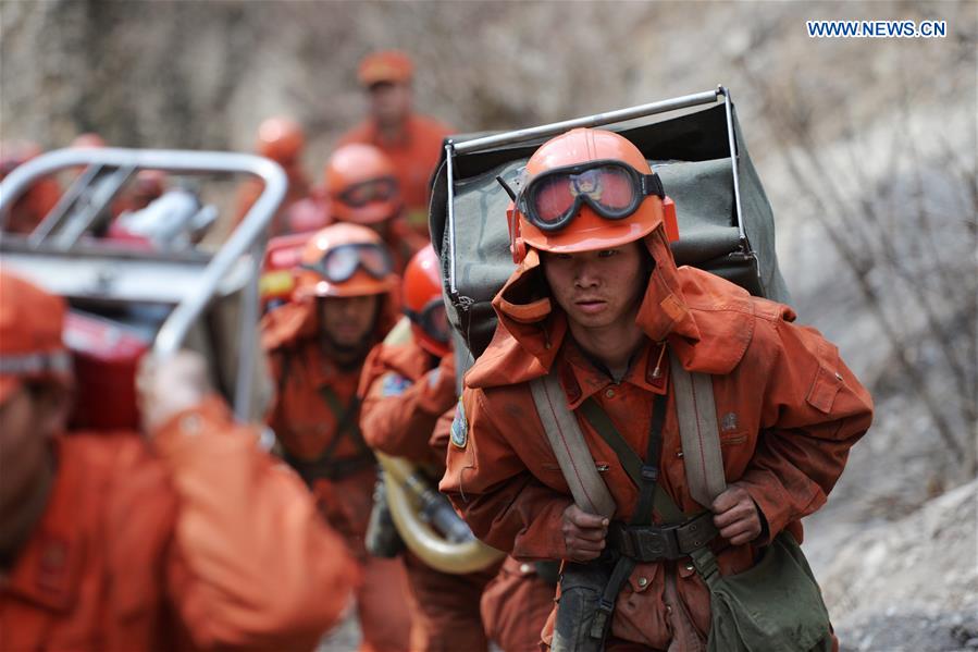 Armed police carry equipment to the scene of the fire in the forest zone of Dala in Tebo County, northwest China's Gansu Province, March 9, 2016. The fire, which was spotted on March 2, has been basically extinguished Wednesday. [Photo/Xinhua]