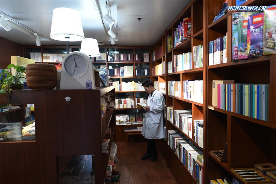 A medical staff member reads in Xiaofeng bookstore, inside Zhejiang Provincial People's Hospital in Hangzhou, capital of east China's Zhejiang Province, March 9, 2016. Xiaofeng bookstore was offered 80 square meters space by Zhejiang Provincial People's Hospital free of charge to provide services for patients, accompanying people and medical staff with more than 3,000 books. [Xinhua]