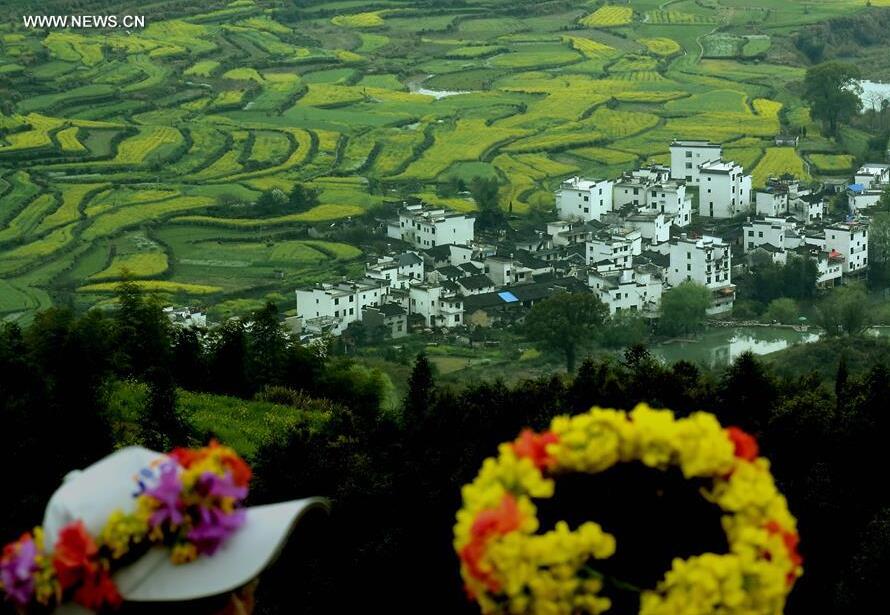 Tourists wearing flower-decorated hats view the terraced fields in Jiangling Village of Wuyuan County, east China's Jiangxi Province, March 31, 2015. China has perfected the art of building terraced fields as an effective way to preserve water and soil, and had a long history of terracing the ridges for high-yield cropping. (Xinhua/Wang Song) 