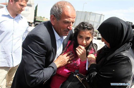 The parents of Palestinian girl Dima al-Wawi, 12, who is believed to be the youngest female detained by Israel, hug her upon her release from Israeli prison, at Israeli military checkpoint near the West Bank city of Tulkarem on April 24, 2016. [Photo/Xinhua]