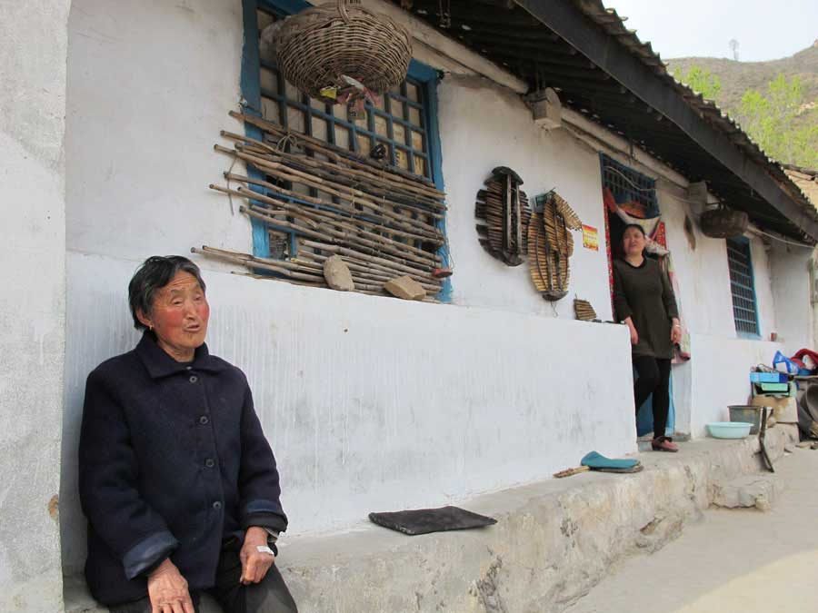 Tang Ronglai, 78-year-old, and her daughter in front of their new house in poverty-stricken Luotuowan village, Fuping county in North China's Hebei province, April 25, 2016. [Photo by Wu Yan/chinadaily.com.cn] 