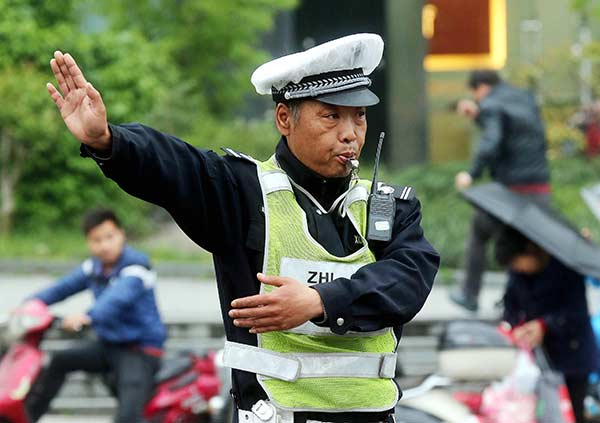 Auxiliary traffic officer Li Weiqi on duty in Hangzhou, Zhejiang province, on Tuesday. Li's quick thinking at the same intersection last week prevented a major tragedy. [Photo/China Daily]