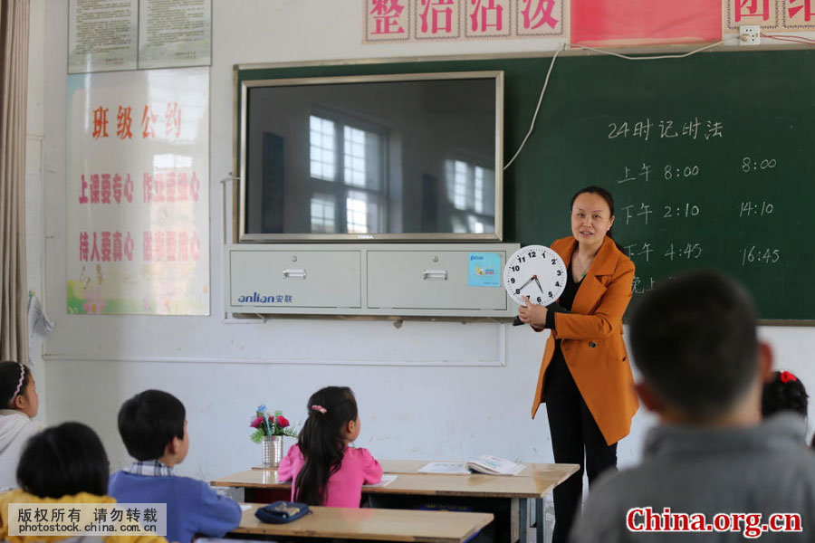 With a clock in her hands, Wu Songyan teaches students the concept of time at Gongping Primary School located in Goudong Village, Renqiao Town, of Bengbu City in Anhui Province, on April 18, 2016. [Photo by Li Bin/China.com.cn]