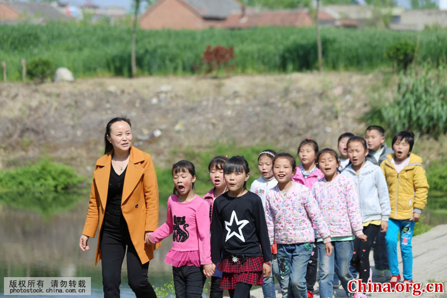 Wu Songyan and her students walk along a field path in Goudong Village in Renqiao Town of Bengbu City, Anhui Province, on April 18, 2016. [Photo by Li Bin/China.com.cn]