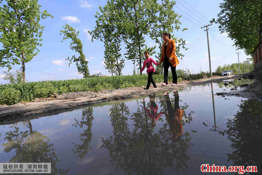 Wu Songyan and a student walk along a field path in Goudong Village, part of Renqiao Town of Bengbu City, Anhui Province, on April 18, 2016. [Photo by Li Bin/China.com.cn]