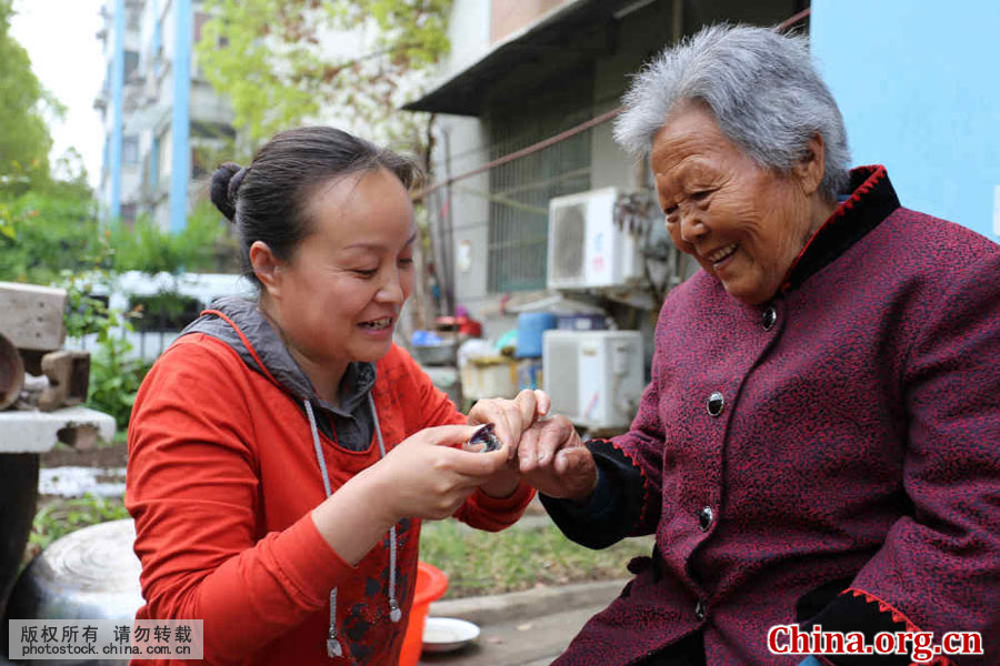 Wu Songyan helps her 94-year-old grandmother cut her nails in Renqiao Town of Bengbu City, Anhui Province, on April 16, 2016. [Photo by Li Bin/China.com.cn]