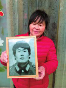 A photo taken on March 10, 2016 shows Wu Wenying holds a portrait of her husband Hou Shuwei, who was tortured to death on May 22, 1997 at the age of 33. [Photo: hsw.cn]