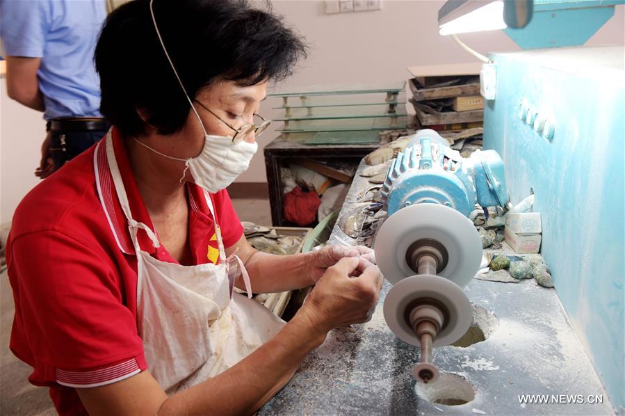 Carving craft master Shi Yexiu carves shells at a museum in Beihai, south China's Guangxi Zhuang Autonomous Region, May 3, 2016. Local workers have used skills of Chinese painting and embroidery in the process of shell carving in recent years. [Xinhua]