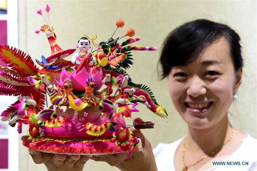 Dough figurine artist Li Jing shows her work during a craft workshop in Jinan, capital of east China's Shandong Province, May 5, 2016. Traditional dough figurine has been listed as China's national intangible cultural heritage. [Photo/Xinhua]