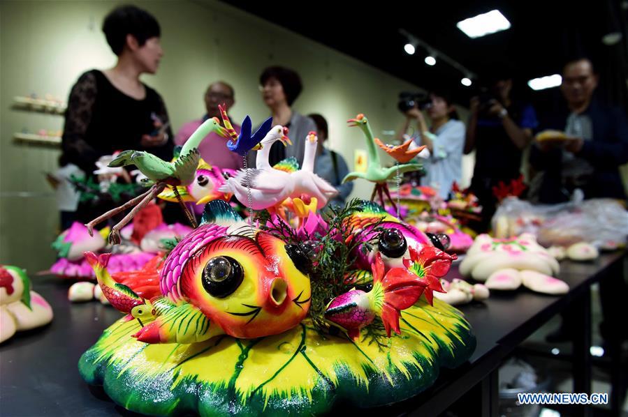 People view delicate dough figurine works in an exhibition hall during a craft workshop in Jinan, capital of east China's Shandong Province, May 5, 2016. Traditional dough figurine has been listed as China's national intangible cultural heritage. [Photo/Xinhua]