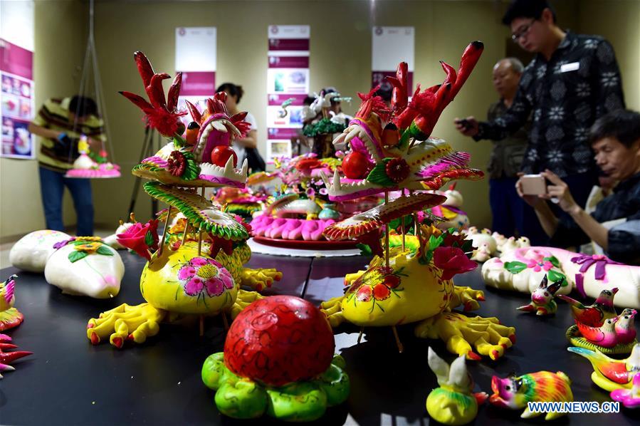 People view delicate dough figurine works in an exhibition hall during a craft workshop in Jinan, capital of east China's Shandong Province, May 5, 2016. Traditional dough figurine has been listed as China's national intangible cultural heritage. [Photo/Xinhua]