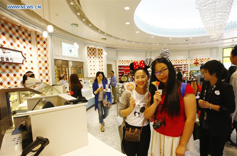 Tourists display newly-bought candies at a dessert shop in the Disney Town of the Disney Resort in Shanghai, May 7, 2016. Two shops in the Disney Town opened here on Saturday, when the Shanghai Disneyland, Disney's first theme park in the Chinese mainland, started an operational test. [Xinhua] 