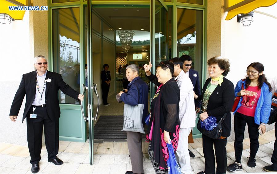 A staff worker pulls the door of a dessert shop for tourists in the Disney Town of the Disney Resort in Shanghai, May 7, 2016. Two shops in the Disney Town opened here on Saturday, when the Shanghai Disneyland, Disney's first theme park in the Chinese mainland, started an operational test. [Xinhua] 