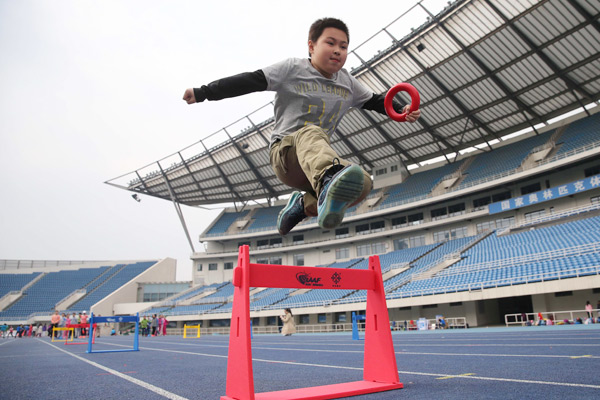 A student practices hurdles at Beijing Primary School in April. Chinese sports stars visited the school and interacted with students to teach them about track and field. [Photo/Xinhua] 