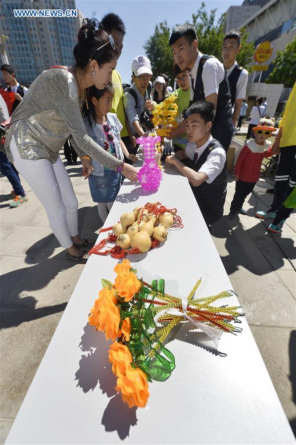 Citizens select handicrafts made by the disabled during a charity sale activity in Yinchuan, capital of northwest China's Ningxia Hui Autonomous Region, on May 15, 2016, the National Day for Helping the Disabled, which is marked on the third Sunday of May every year. [Photo/Xinhua]