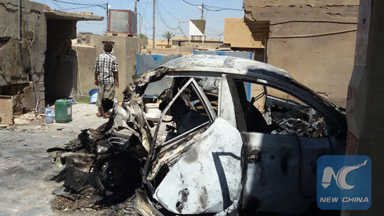 A man stands by a damaged car which was hit by a projectile launched by the Iraqi Force against the Islamic State militants in Fallujah, Iraq, on May 24, 2016. [Photo/Xinhua]