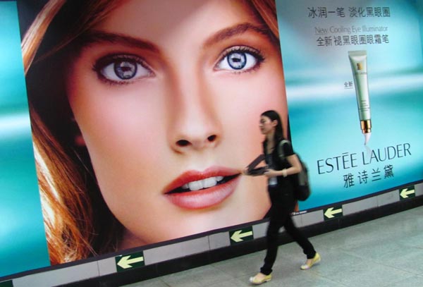 A passenger passes by a banner for Estee Lauder cosmetics, July 2, 2011. [Wu Changqing/For China Daily] 