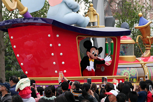 Visitors take photos during a parade at the Shanghai Disneyland park. [Photo/Xinhua]