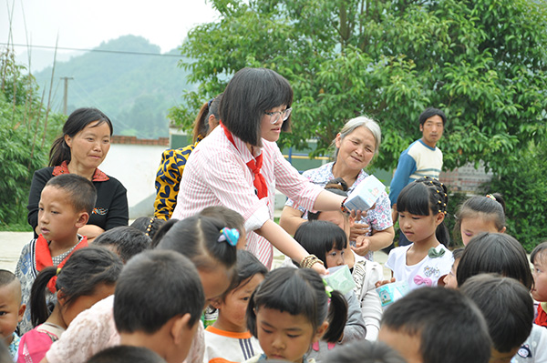 Liu Jiaying (wearing glasses) distributes gifts to students at Shaba primary school in Qianxi county, Guizhou province while visiting the school for the launch ceremony of the first Flying Box project in June, 2015. [Photo/China Daily]