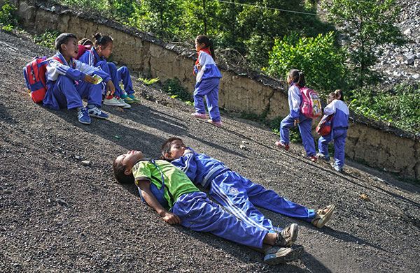 Children from Atuler village in Sichuan province take a rest during their regular long trudge to school. [Photo/China Daily]