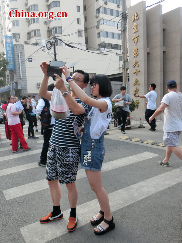 Parent and student are taking selfie after the examination, they want to record this moment together, show that they been through this tough situation together. [Photo by Yu Winglam / China.org.cn]