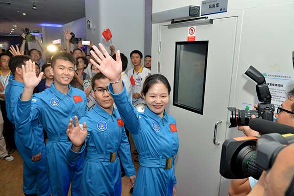 Four volunteers wave to the cameras before starting a six-month living experiment in an enclosed space capsule in Shenzhen, Guangdong province, on Friday. The project is designed to support China's deep-space exploration plan. [Photo/Xinhua]
