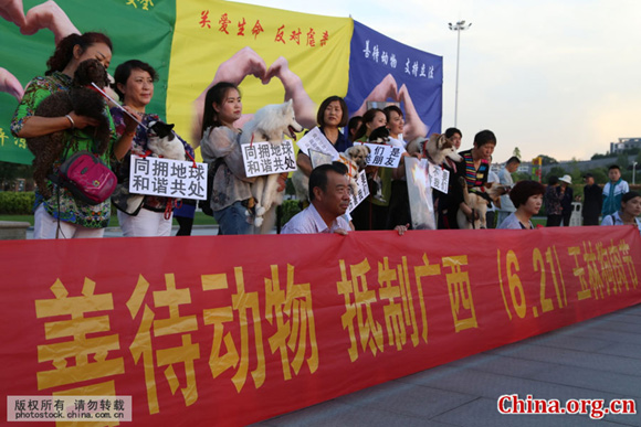 More than 30 people, along with their dogs, gather in downtown Pingliang, Gansu Province, on June 12 to protest the upcoming Dog Meat Festival in Yulin, Guangxi Zhuang Autonomous Region. The red banner reads: 'Fair treatment for animals. Boycott the June 21 Guangxi Yulin Dog Meat Festival.' [Photo by Zheng Bing/China.com.cn]