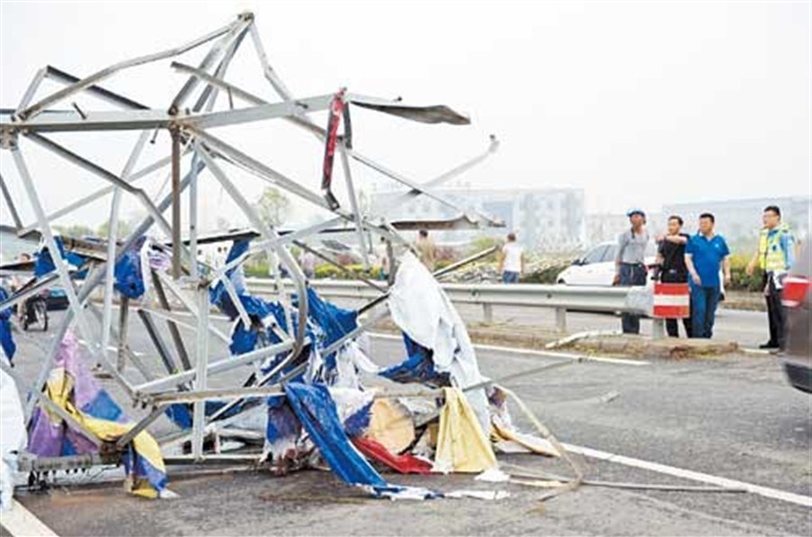 Residents look at the wreckage of a tower after strong gales hit Yancheng in Jiangsu Province yesterday. 