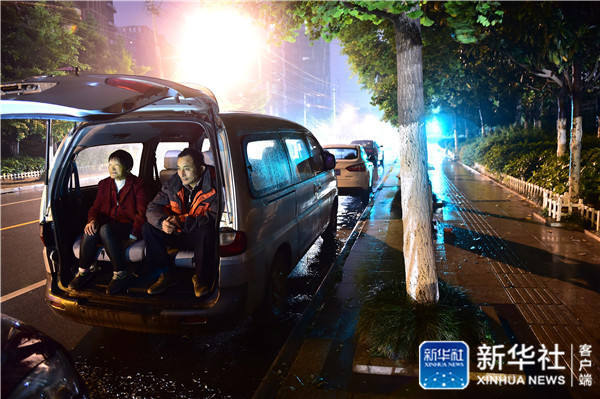 Parents seek shelter from heavy rain in a minivan while waiting to apply for a private kindergarten in Hefei City, Anhui Province on May 9. [Photo by Xinhua News Agency] 