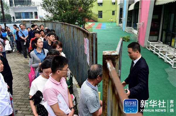 Parents queue to get their children a chance to participatein the admission lotteryfora private kindergarten in Hefei City, Anhui Province on June 6. [Photo by Xinhua News Agency] 