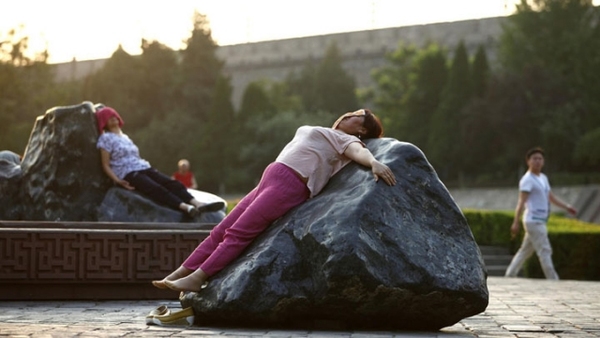 A women lies on the heated landscape stone in Xi'an, capital of Shaanxi province on June 24, 2016. [Photo: Cankaoxiaoxi.com] 
