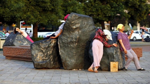 A group of women lie on the heated landscape stones in Xi'an, capital of Shaanxi province on June 24, 2016. [Photo: Cankaoxiaoxi.com] 