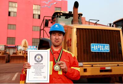 Guo Kai displays his Guinness world record certificate in front of his wheel loader. [File photo]