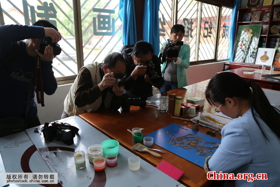 在甘肃省平凉市静宁县成纪掐丝画艺廊，工艺师绘画现场吸引众多摄影爱好者围观拍照。[中国网图片库 郑兵 摄]