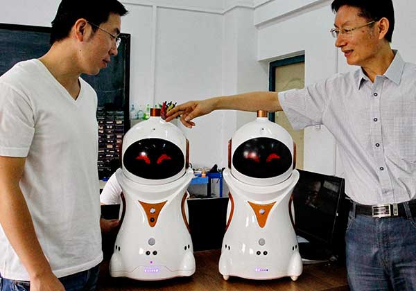 Professor Zhou Fengyu (right) displays the newly developed robots with his colleague.[Ju Chuanjiang/China Daily] 