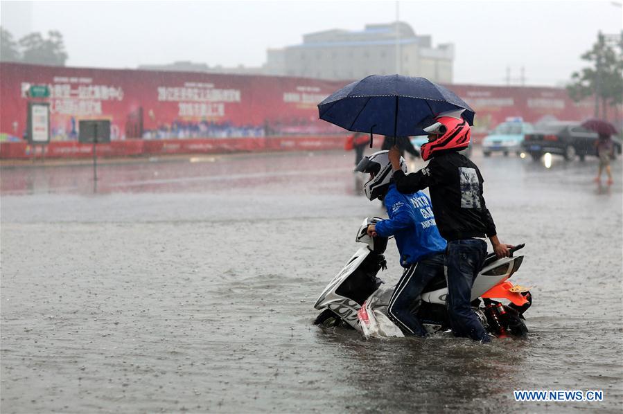 Residents walk on a flooded road in Xingtai, north China's Hebei Province, July 19, 2016. Heavy rain afflicted some regions of north China on July 19, causing serious waterlogging in many cities. [Photo: Xinhua/Hao Yaxin] 