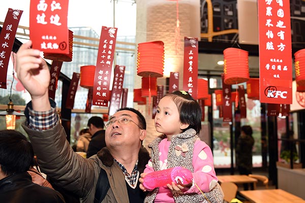 A father and his daughter take part in the riddle-guessing contest at a KFC outlet in Zhengzhou, capital of Henan province, during this year's Lantern Festival. (Photo/China Daily) 